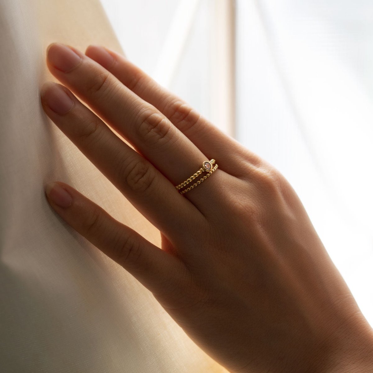 Gold vermeil solitaire rope ring with a clear stone, shown on a model's finger