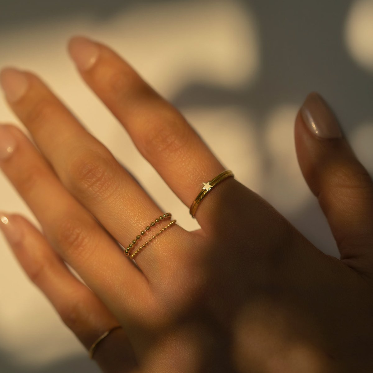 Gold-filled tiny star ring stacked with a beaded ring, shown on a hand