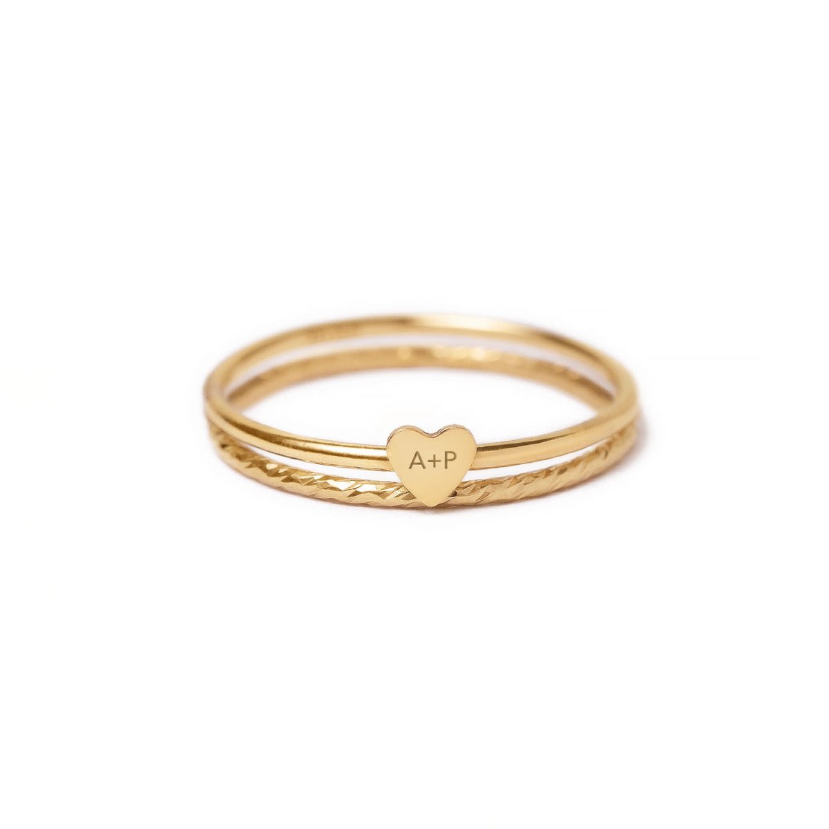 Gold-filled tiny heart stacker ring set engraved with initials, on a white background