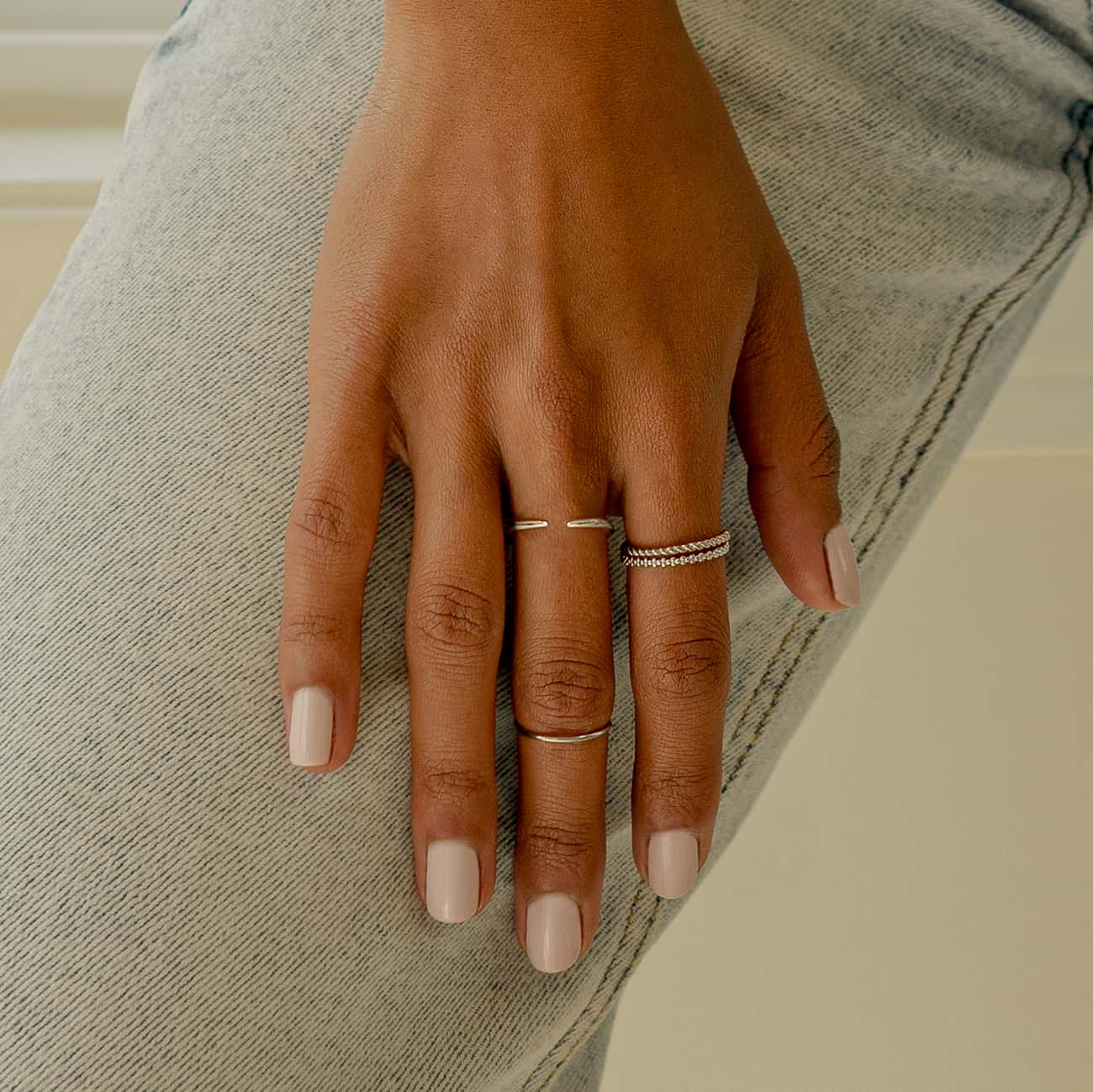 Sterling silver eternity bead ring stacked with thin bands, shown on a model's hand