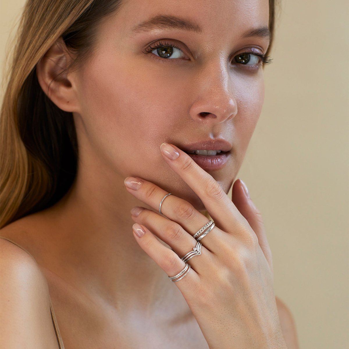 Sterling silver chevron ring with a clear stone, stacked on a model's finger near her face