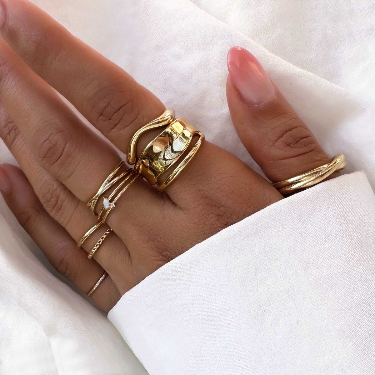 Gold vermeil melted wide band statement ring stacked on a hand, shown on a model's finger
