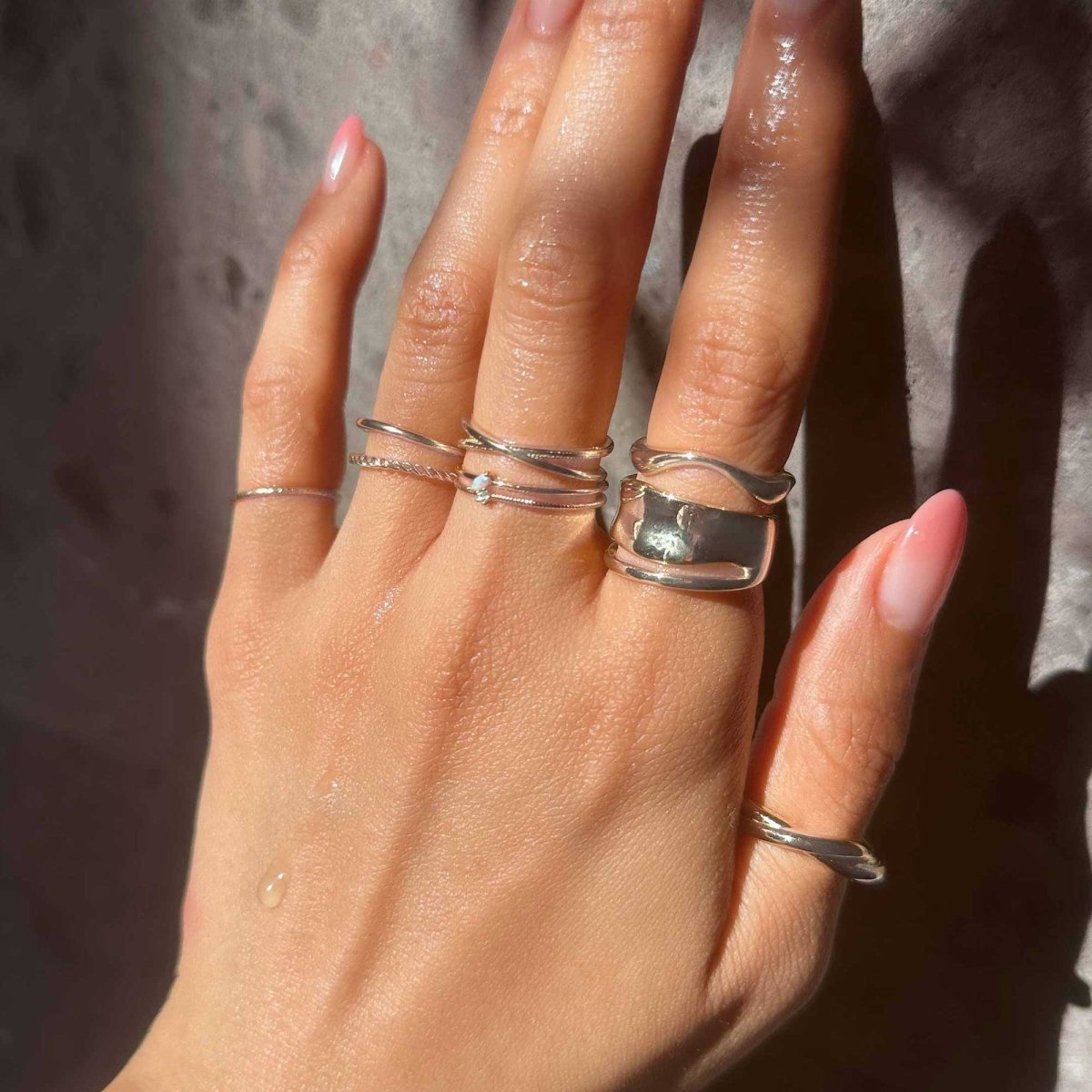 Sterling silver rope-twist double-band stacking ring worn in a stack on a model's hand
