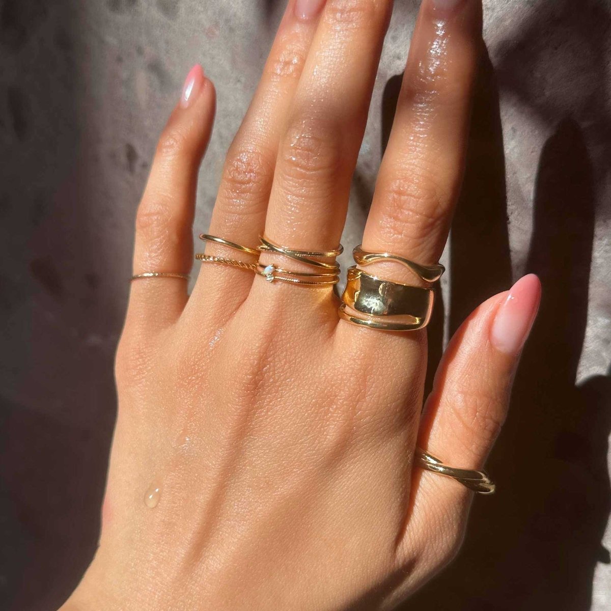 Gold vermeil X stacker ring shown on a model's finger in a stack of gold rings
