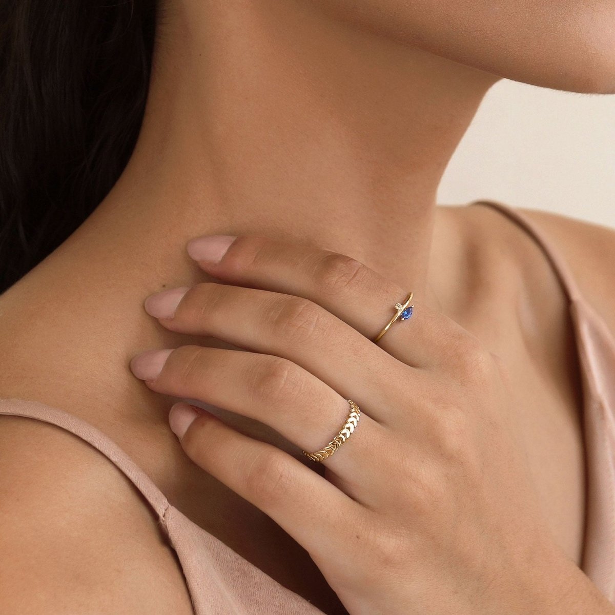 Gold vermeil blue sapphire marquise ring with a small clear accent stone, worn on a model's hand