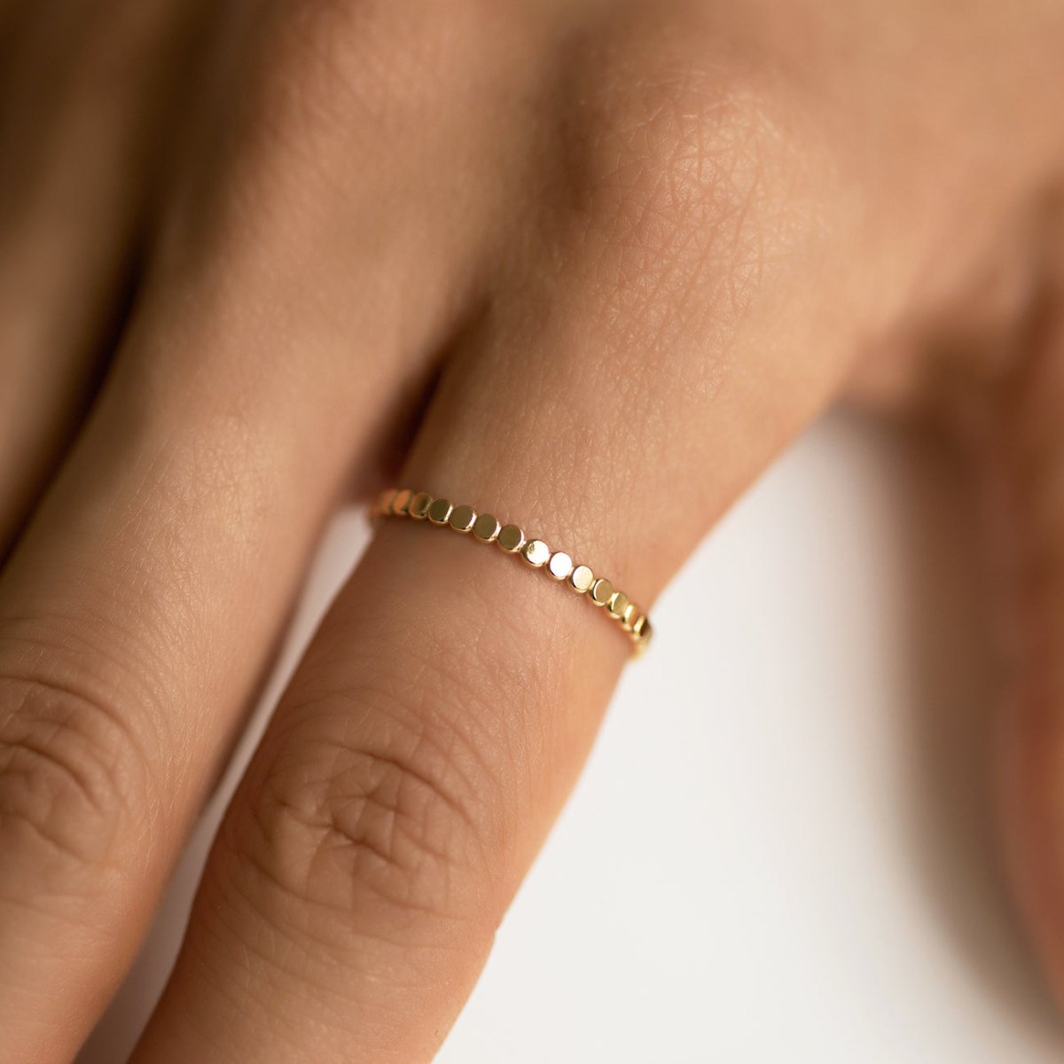 Gold-filled flat beaded thin band ring, shown on a model's finger