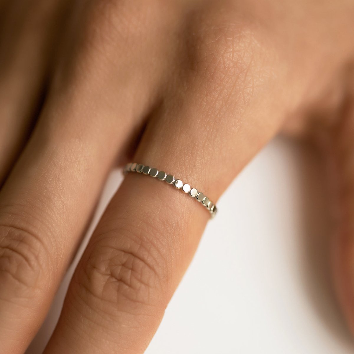 Sterling silver flat beaded thin band ring, shown on a model's finger