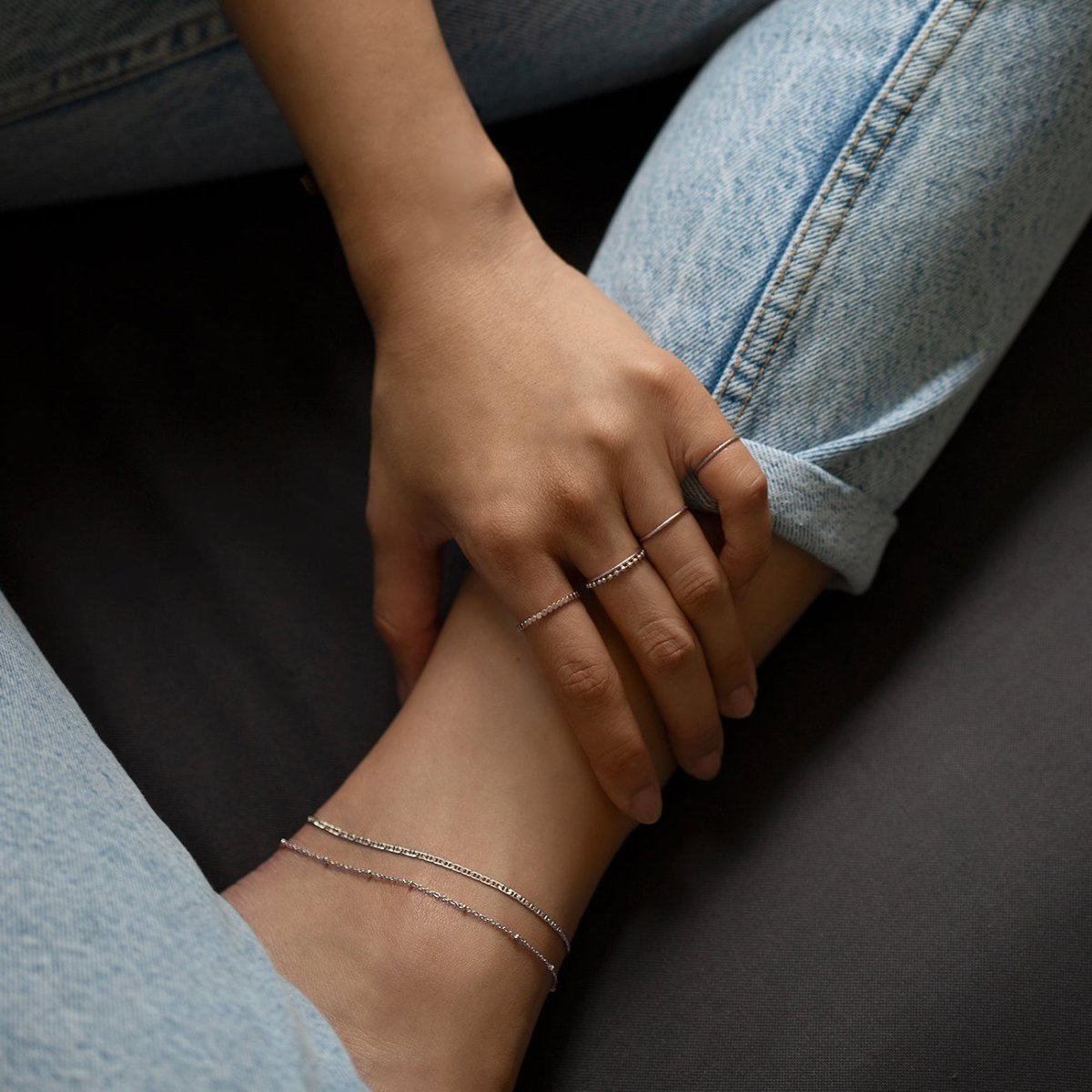 Sterling silver beaded chain bracelet layered on a model's wrist with stacked rings