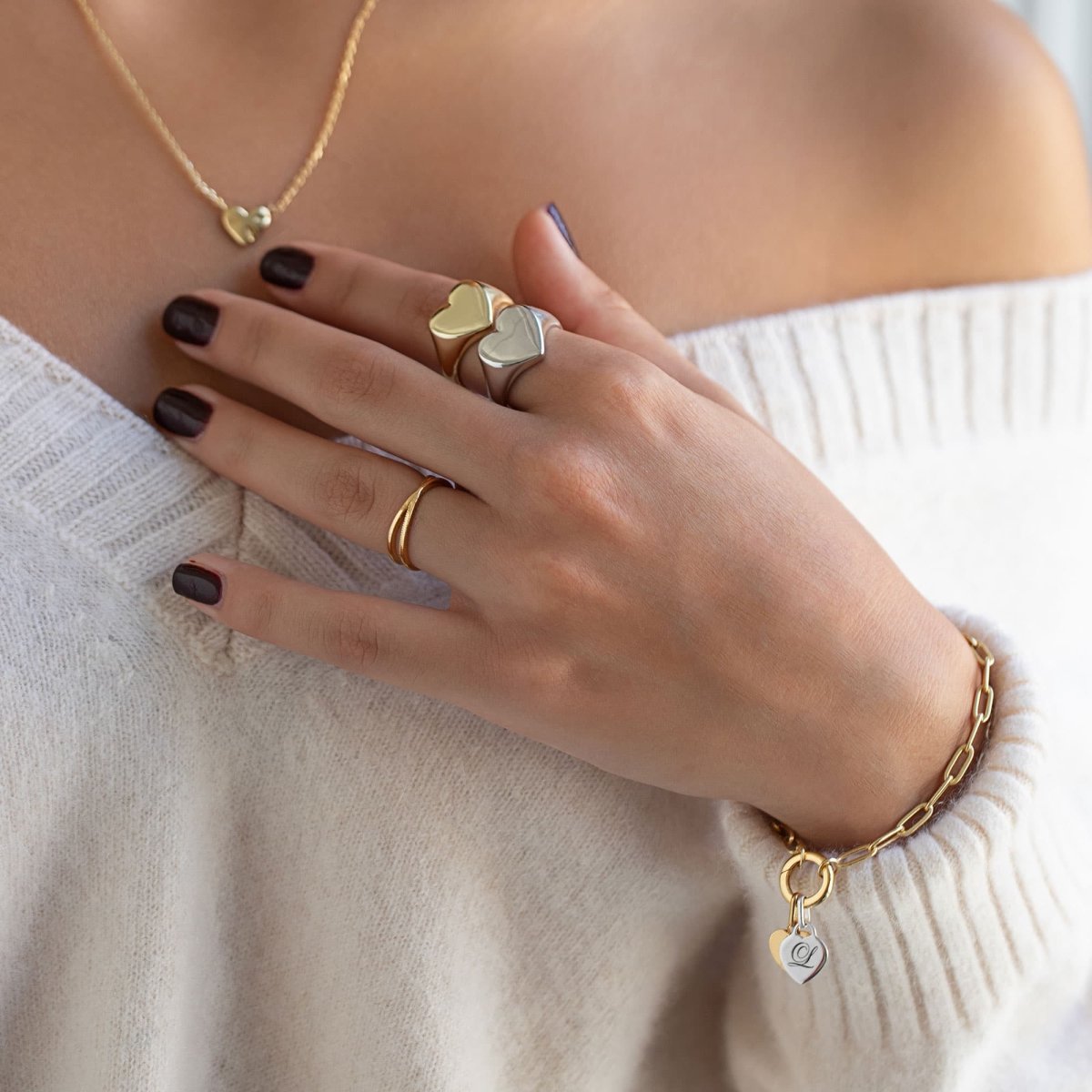 Gold vermeil and silver heart charms on a paperclip bracelet, shown on a model's wrist and hand
