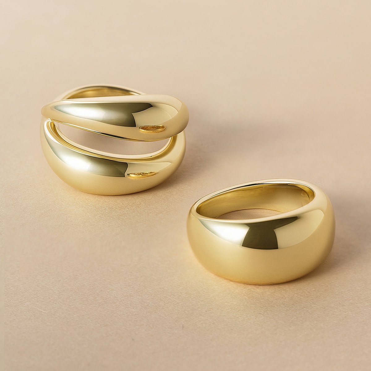 Gold double-band dome ring beside a single dome ring, on a cream background