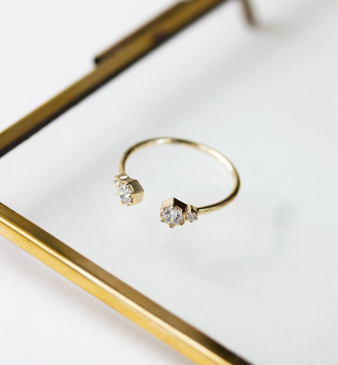 Gold vermeil open cuff ring with clear zirconia stones, resting on a glass tray