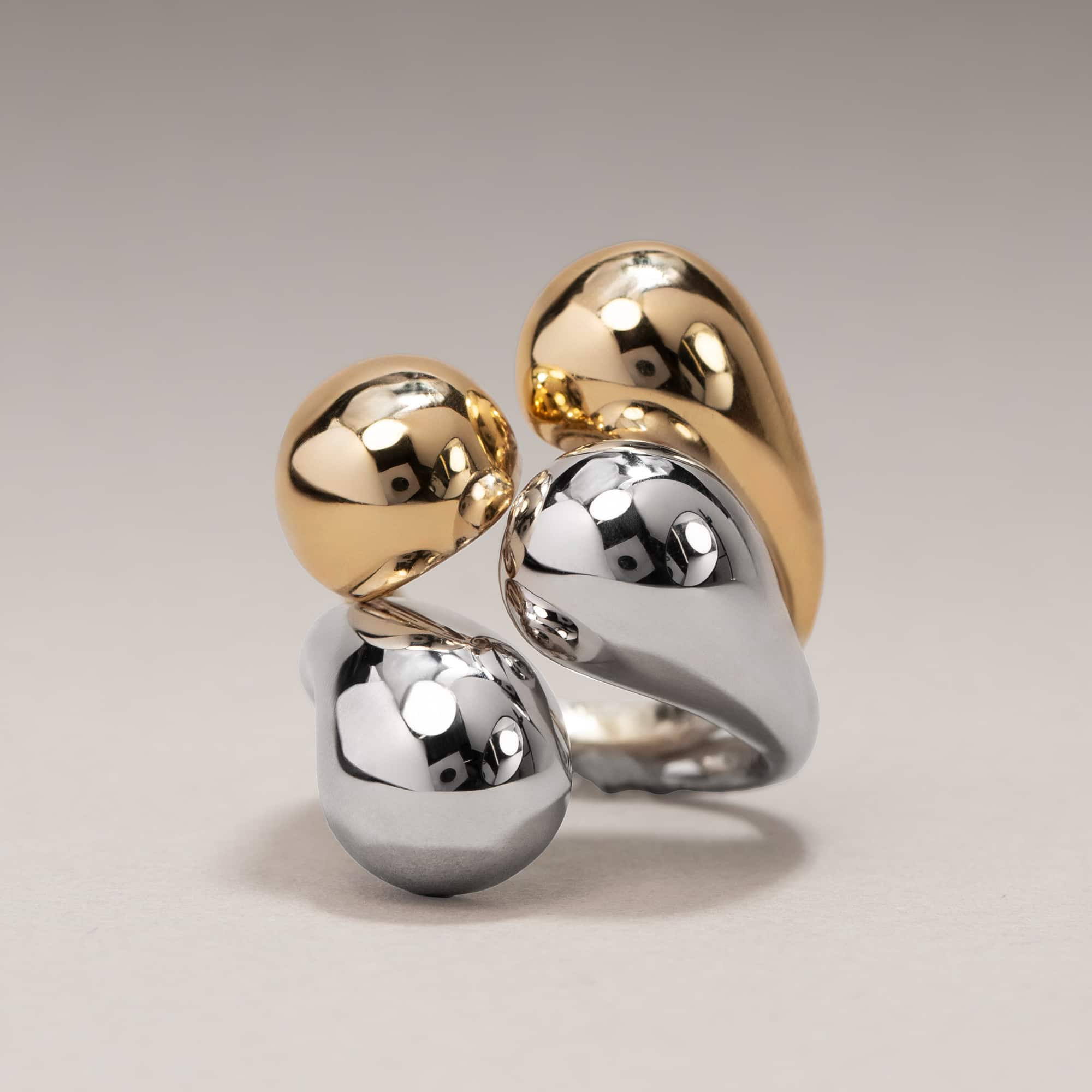 Gold vermeil and sterling silver sculptural bypass rings stacked together, on a cream background