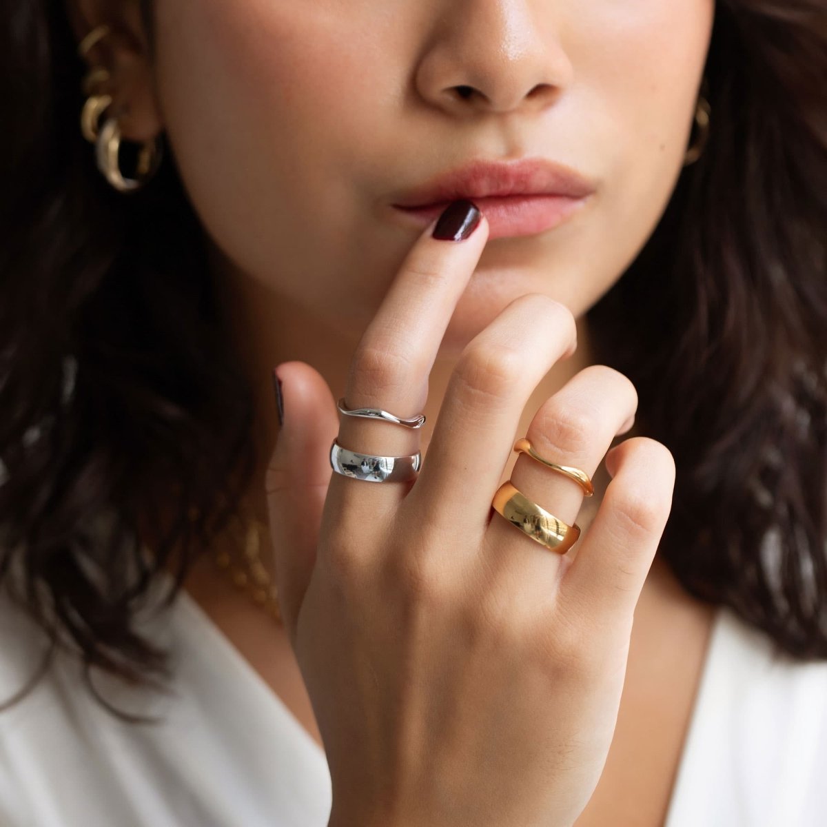 Sterling silver wavy stacking band shown with gold and silver rings on a model's fingers
