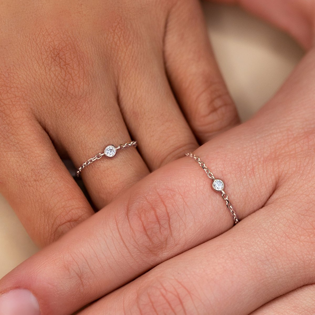 14K white gold diamond chain rings with bezel-set round diamonds, shown on two of a model's fingers