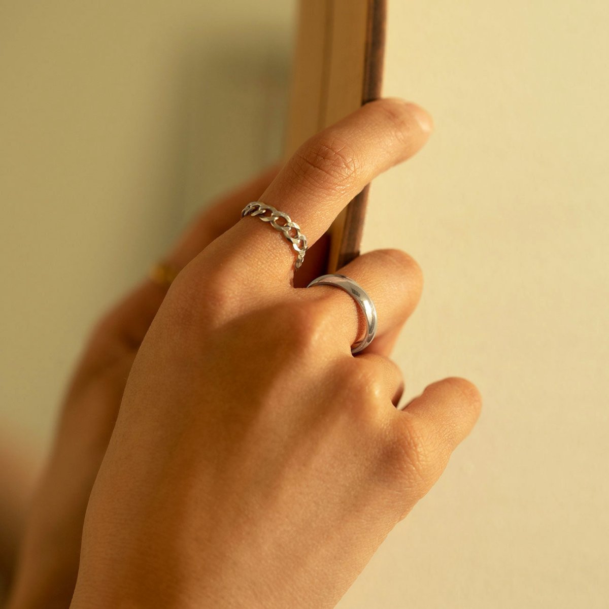 Sterling silver thick domed band ring shown on a model's finger by a chain ring