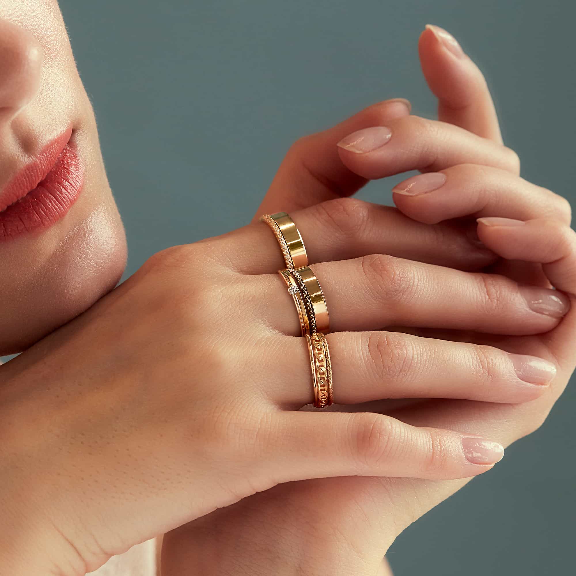 Gold vermeil ring set stacked on a model's finger, including a wide band and engraved ring