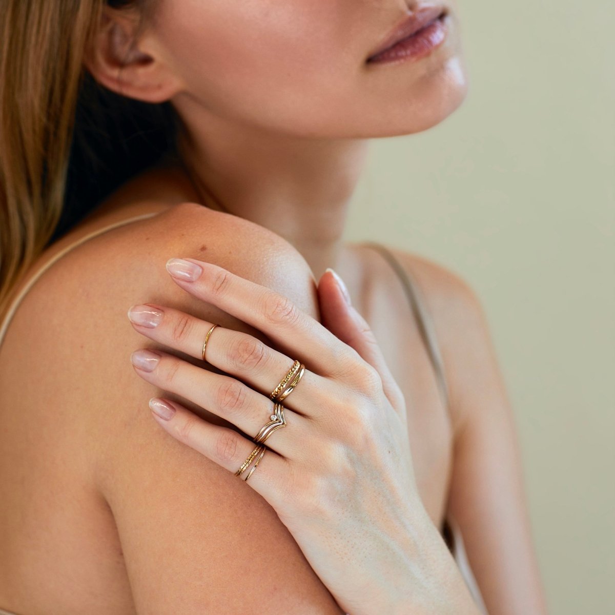 14K gold thin stacking ring worn in a stack across the fingers, shown on a model's hand