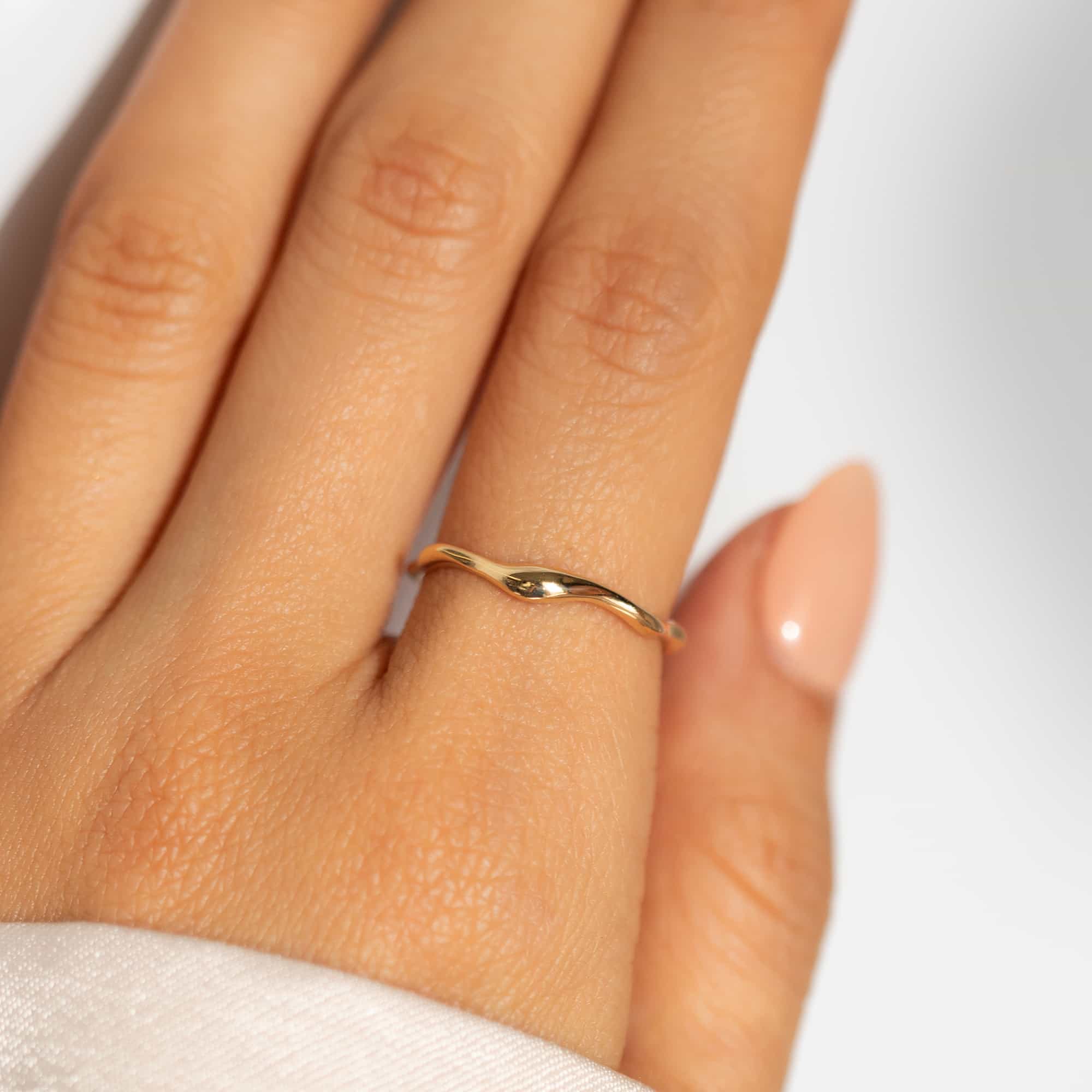 14K gold dainty wave stacking ring shown worn on a model's finger
