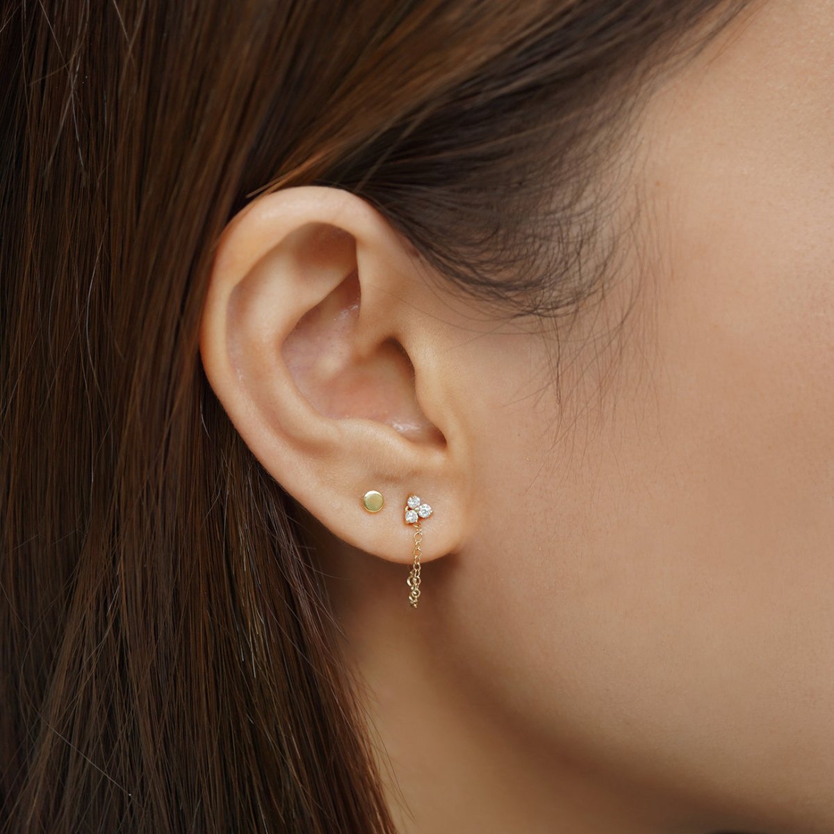 14K gold tiny disc stud worn in a model's first lobe piercing, shown close up