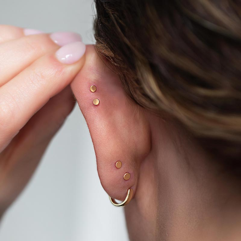 Ear folded forward to show the flat disc backs of flat back earrings