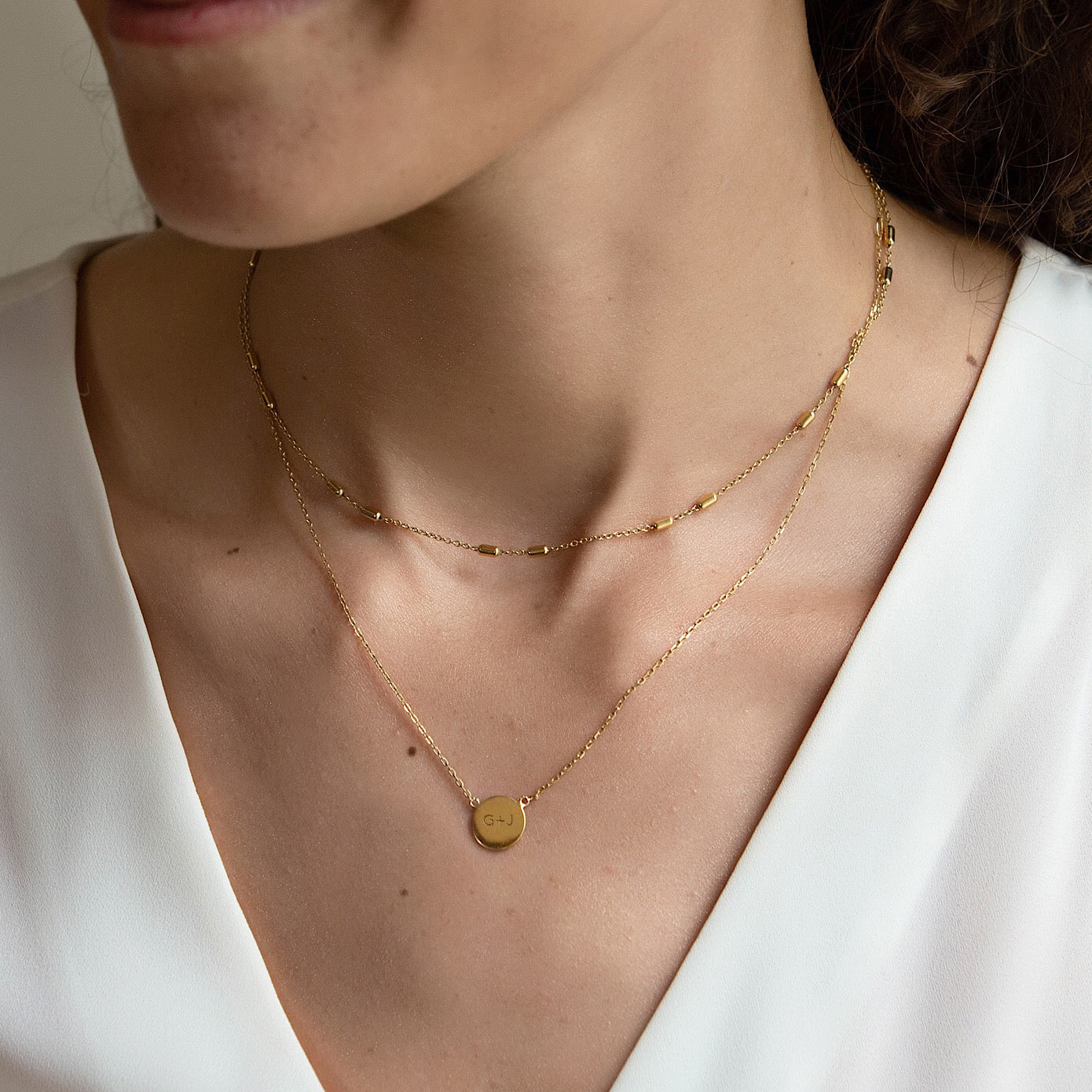 Gold vermeil engravable disc necklace with an initial, layered on a model's neckline