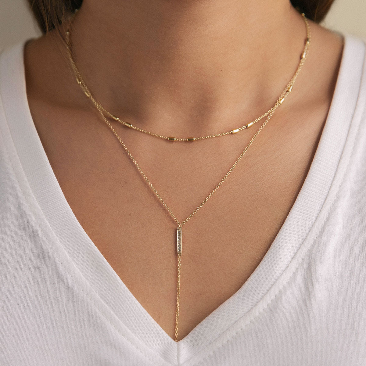 Gold vermeil choker and Y-shaped lariat with a pave bar drop, shown on a model's neckline
