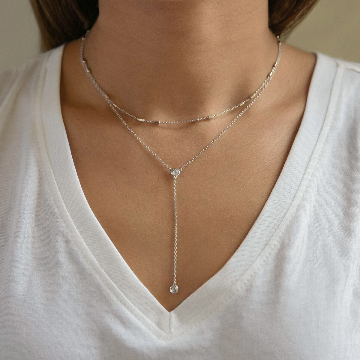 Sterling silver zirconia lariat necklace with a bezel-set drop, shown on a model's neckline