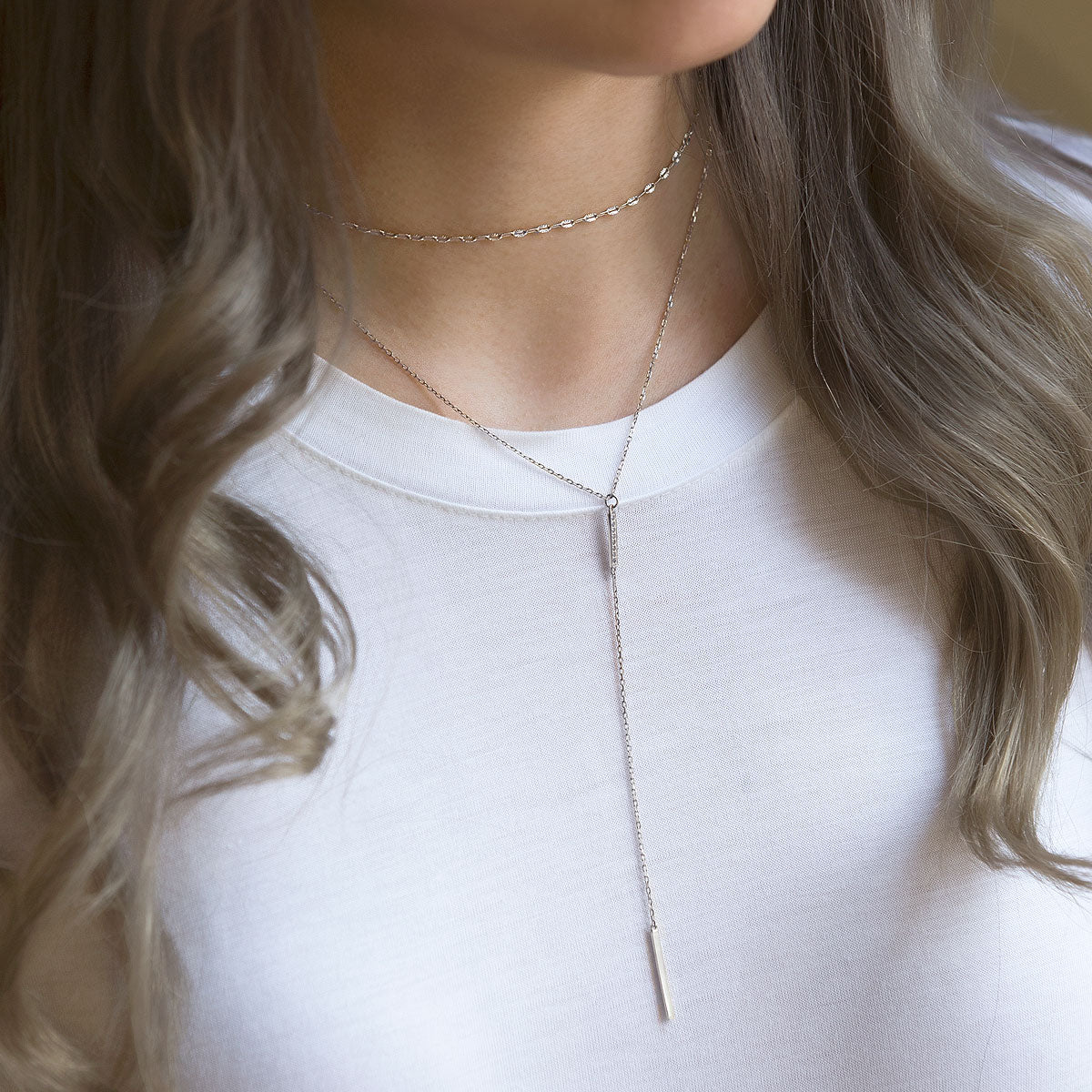 Sterling silver bar lariat layered with a lace chain choker, shown on a model's neckline