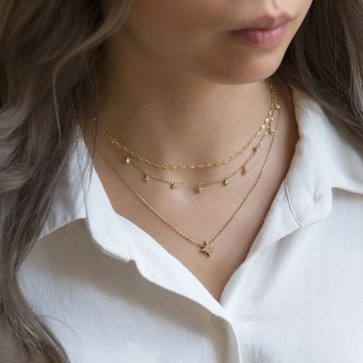 Gold vermeil layered star necklace duo with white zirconia starbursts, shown on a model's neckline