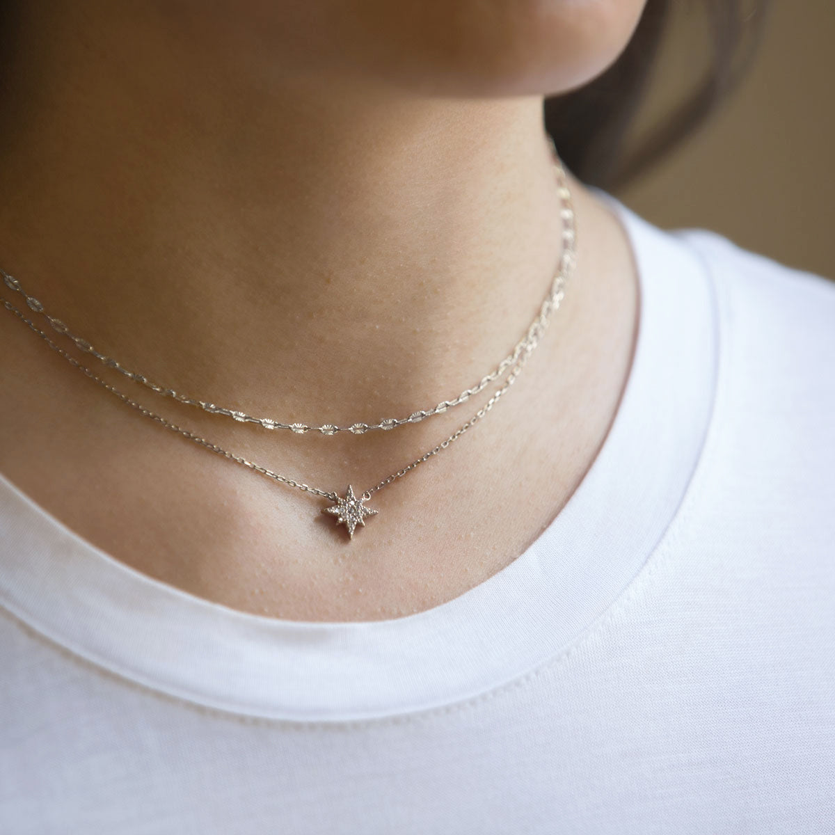 Sterling silver layered duo of a lace chain and a pavé star pendant chain, shown on a model's neckline