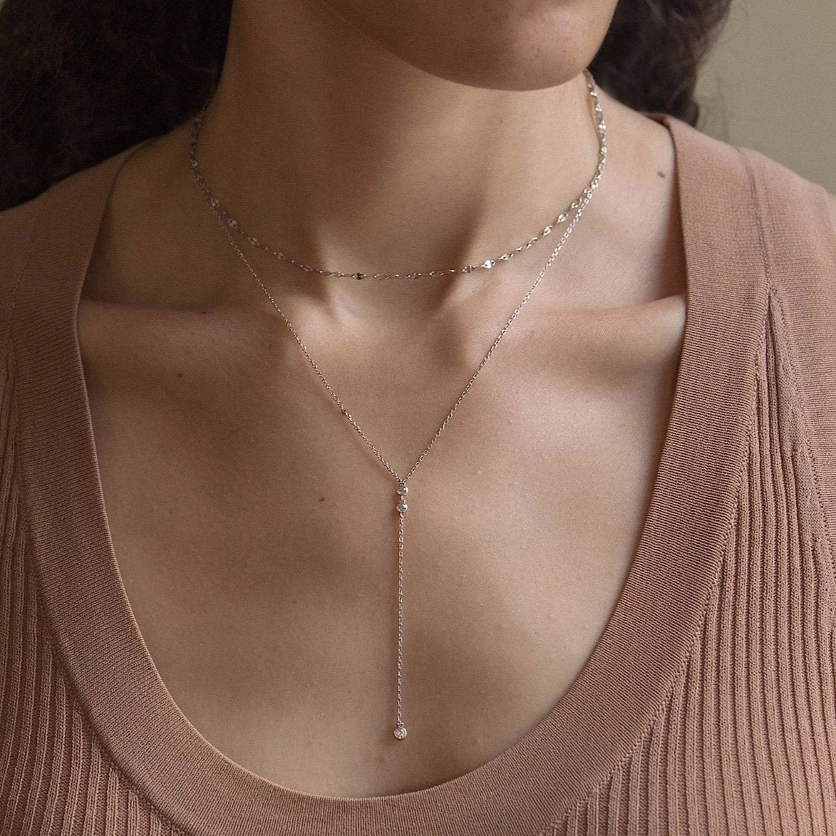 Sterling silver layered lariat duo with a clear stone drop, shown on a model's neckline