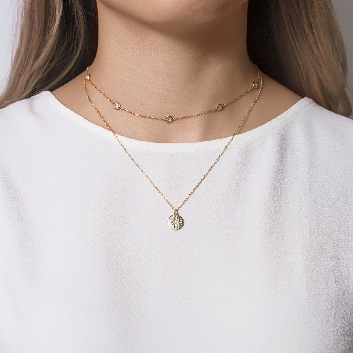 Gold vermeil layered station choker with clear stones and a star-disc pendant, on a model's neckline