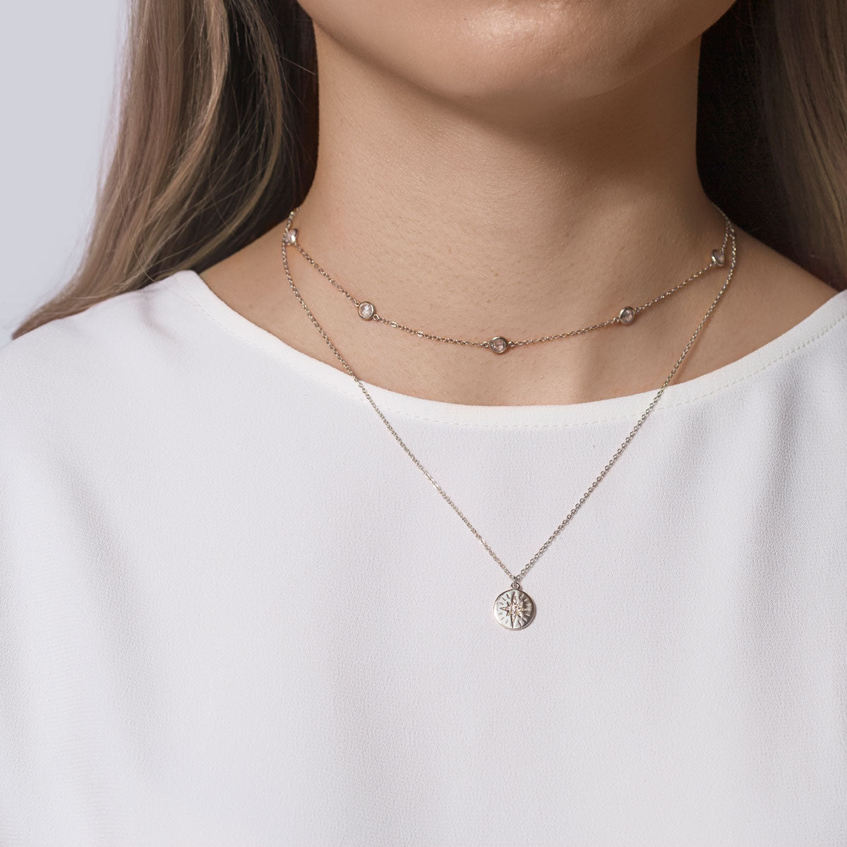 Sterling silver layered choker with clear stones and a star-disc pendant, shown on a model's neckline