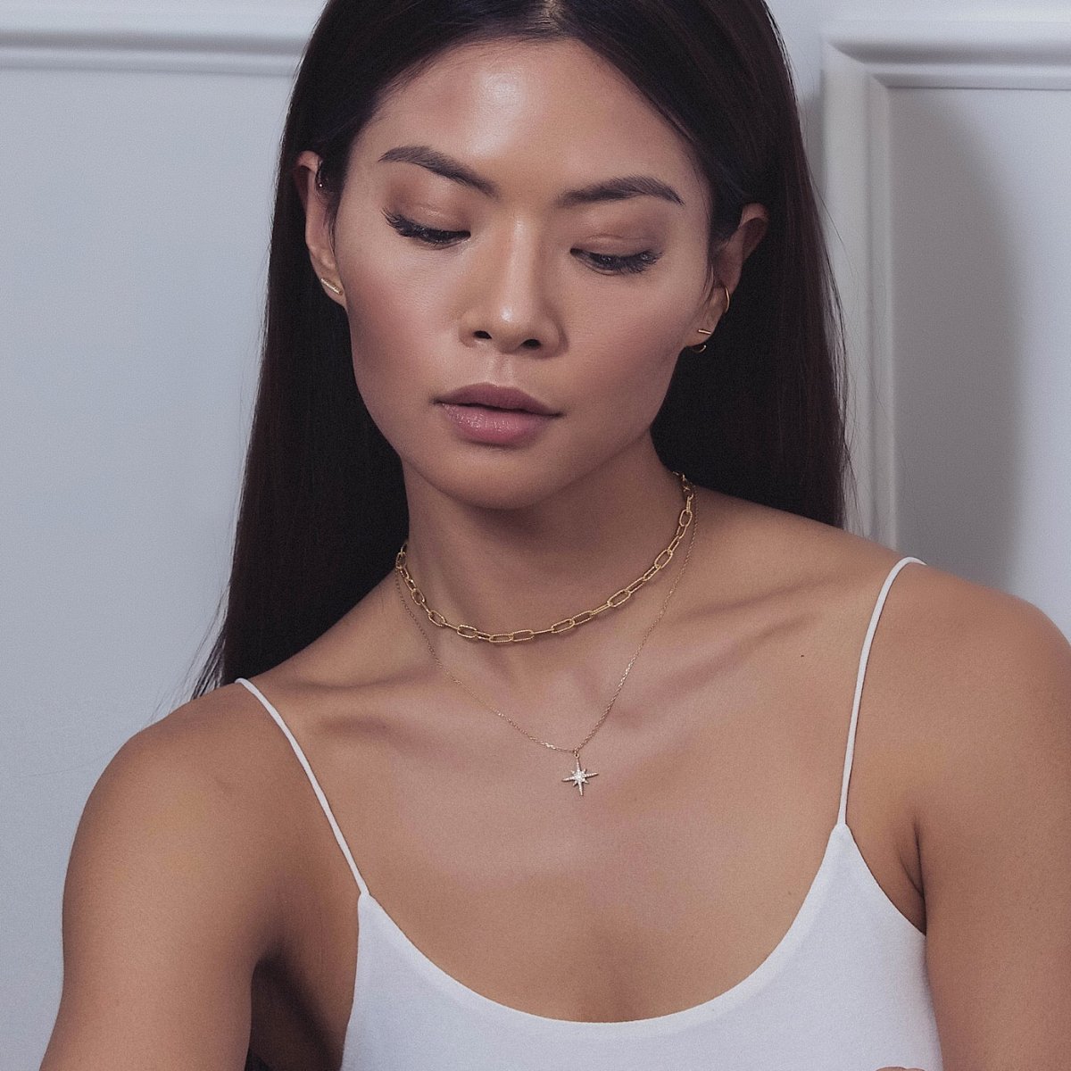Gold vermeil chunky link choker and clear-stone starburst pendant necklace on a model's neckline