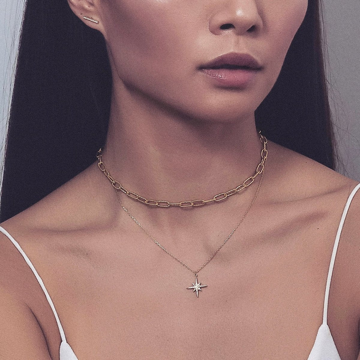 Gold vermeil chunky link chain choker layered with a starburst pendant necklace on a model