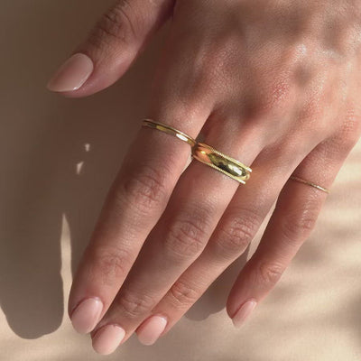 Close up of hand wearing AMYO's Milgrain Band Ring, Hammered Ring, and Thin Stacking Ring