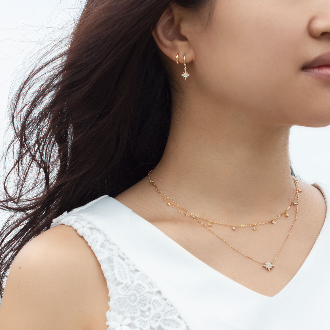 Gold vermeil layered star drop and pavé star pendant chains with a star huggie hoop, shown on a model