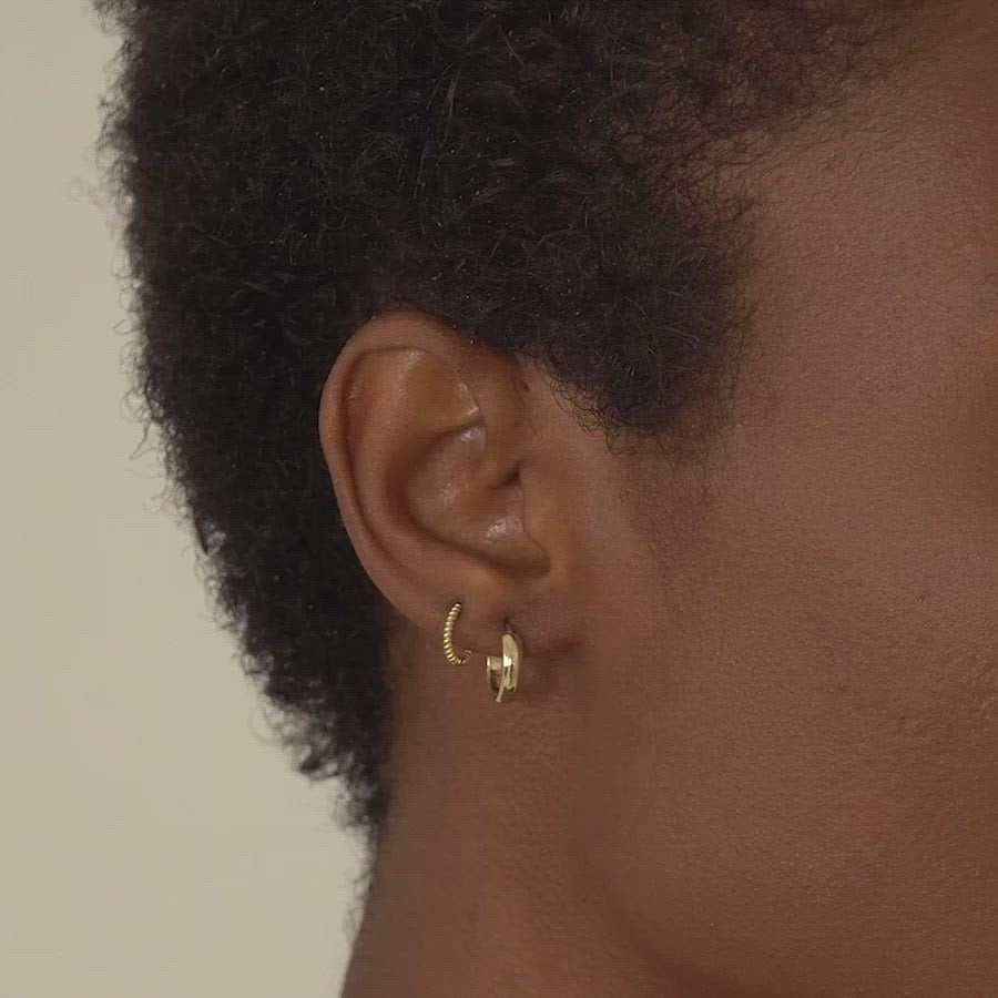 Close-up of woman's ear featuring Amyo Jewelry's Gold Small Rope Textured Gold Huggie Earrings and 14K Gold Boiyfriend Mini Hoops. 