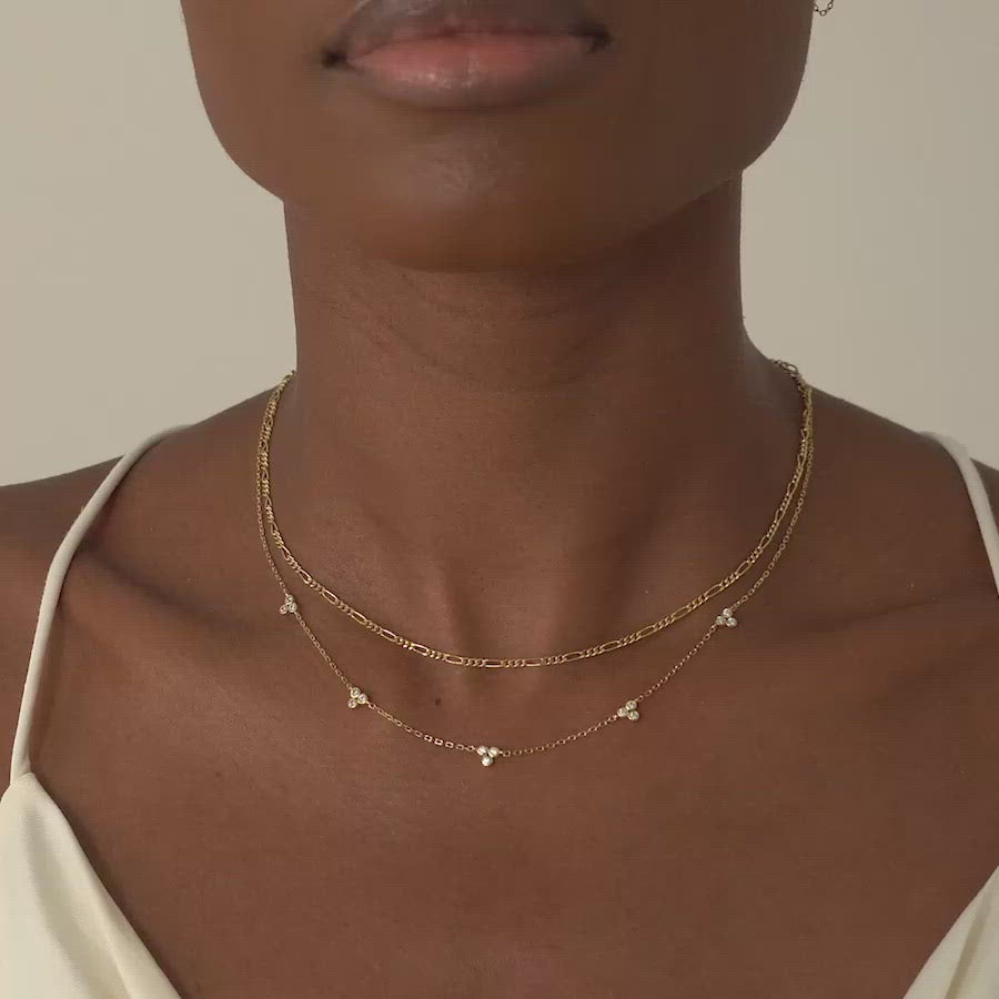 Model wearing a layered look with AMYO's Figaro Necklace and Clover Crystal Necklace in Gold Vermeil