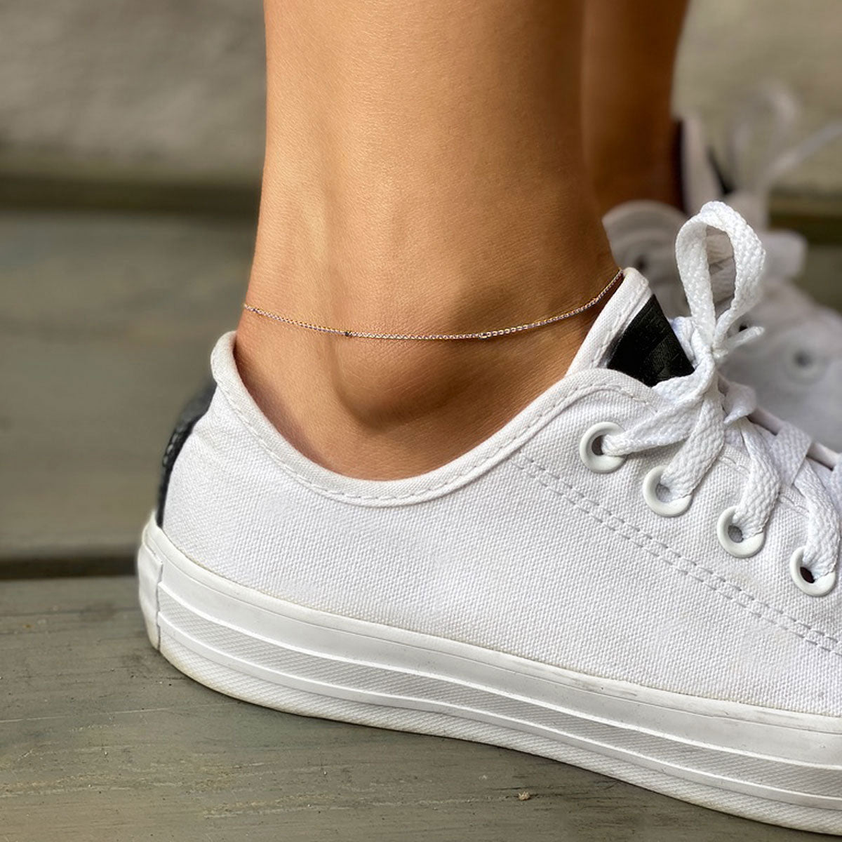 Sterling silver dainty thin chain anklet, shown on a model's ankle with a white sneaker