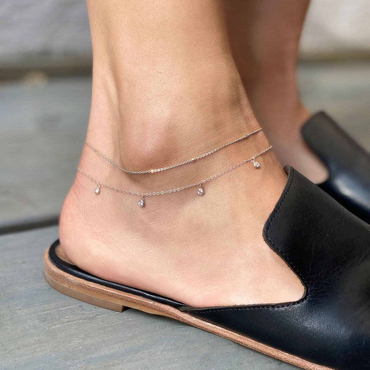 Sterling silver layered anklets with tiny clear stone drops, shown on a model's ankle