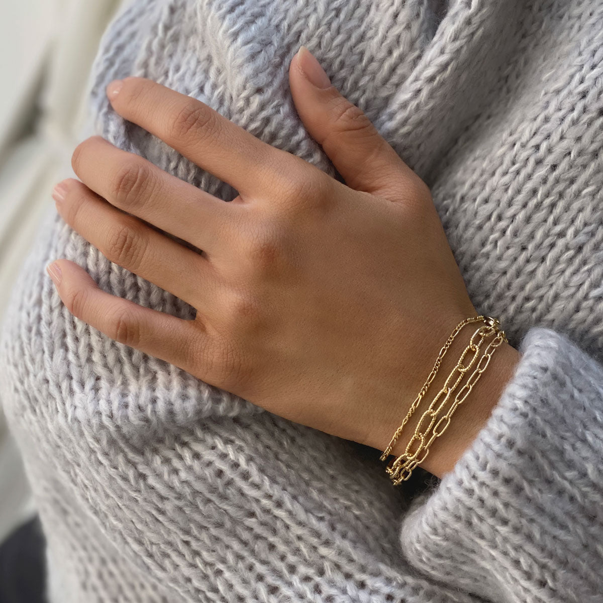 Gold vermeil chunky link chain bracelet worn on a model's wrist against a grey sweater