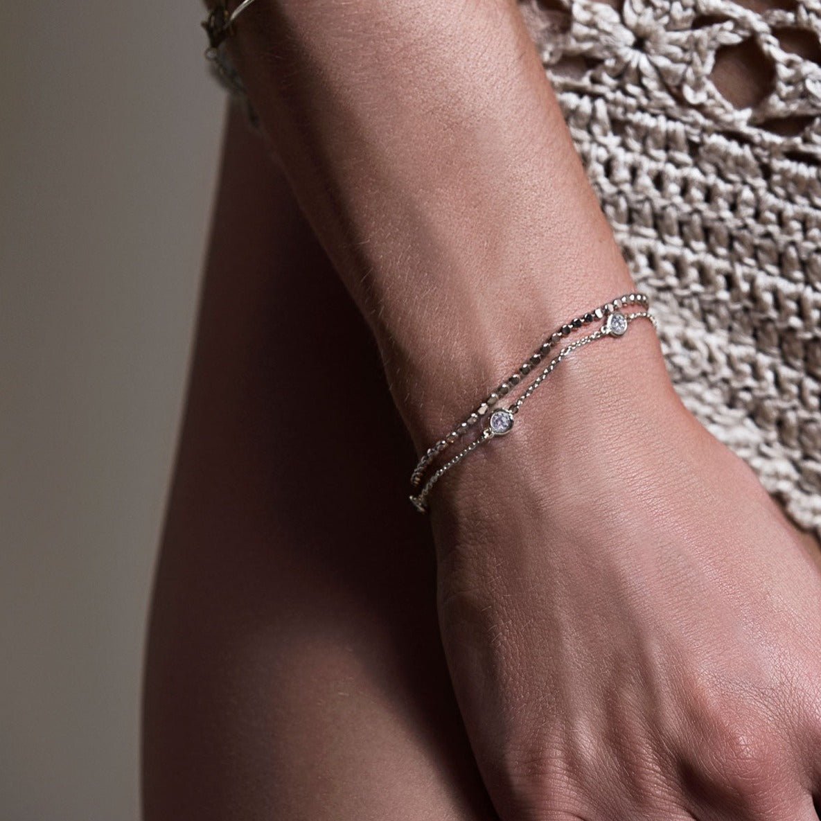Sterling silver beaded chain bracelet with clear stone stations, shown on a model's wrist