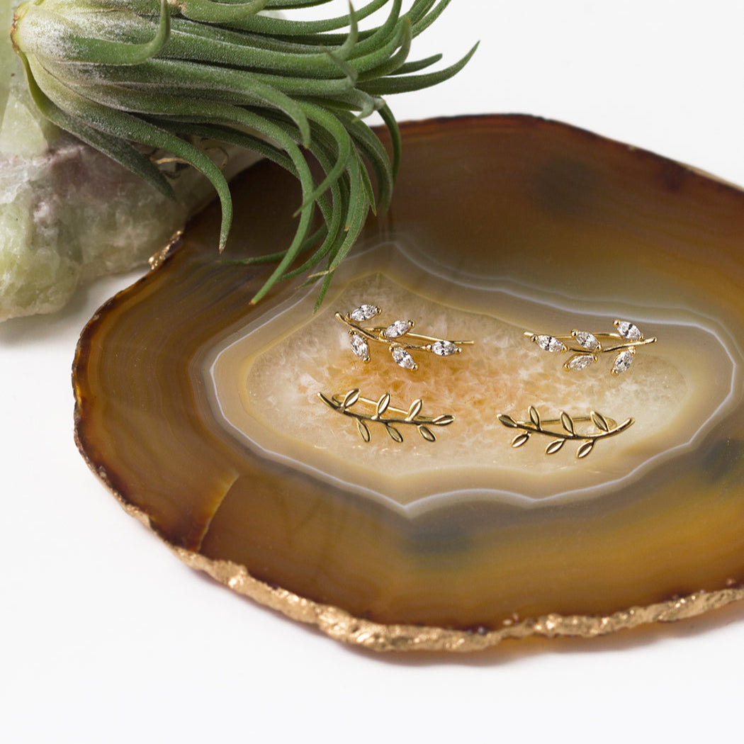 Gold vermeil leaf-and-vine ear climbers, plain and crystal-set pairs, on a brown agate slice