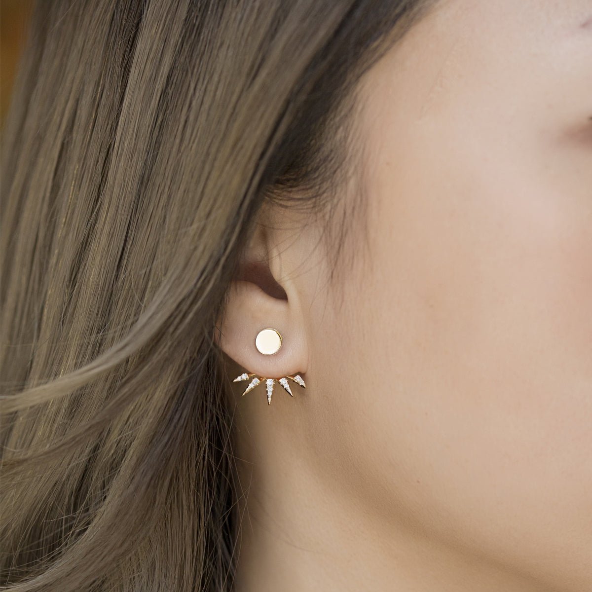 Gold vermeil round stud with a white zirconia spike jacket fanned below, shown on a model's lobe