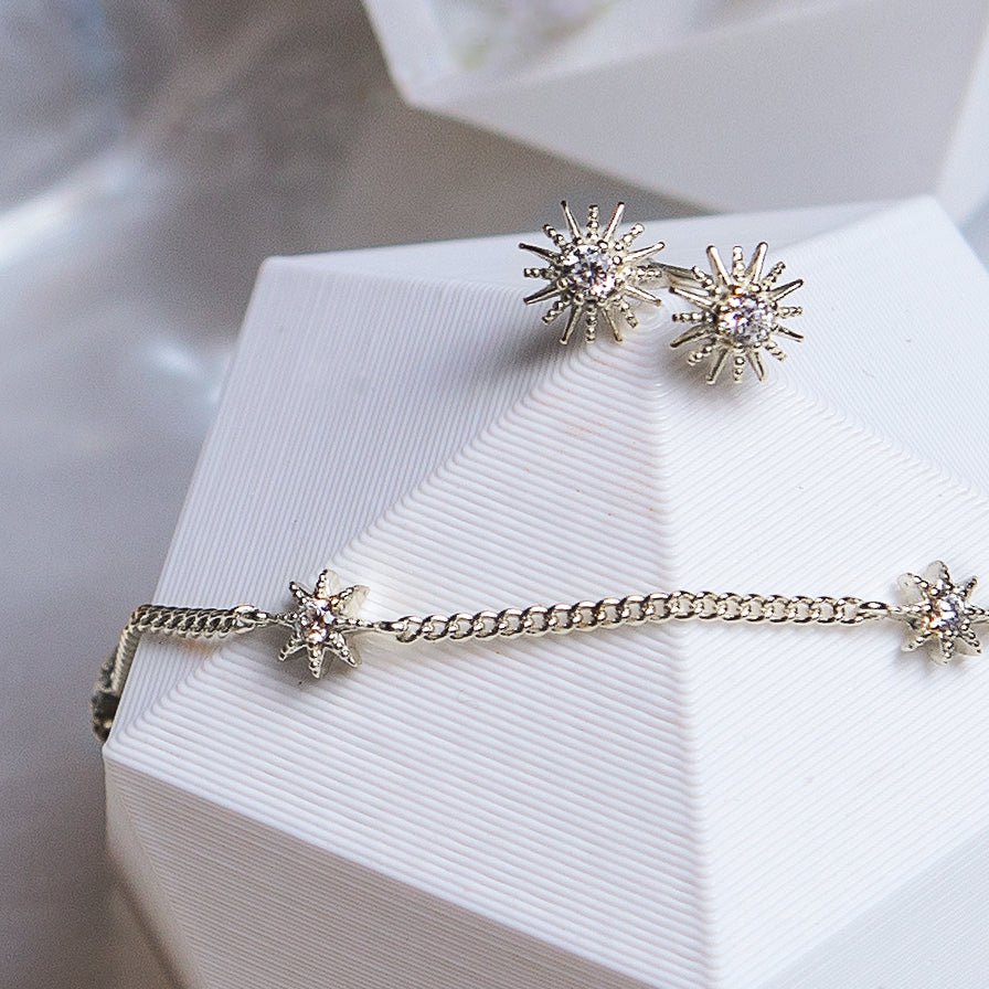 Sterling silver pavé star studs and a star station chain bracelet, on a white prop