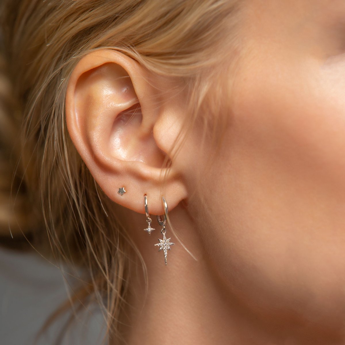 14K white gold pavé huggie hoop with a clear-stone starburst charm, shown on a model's lobe