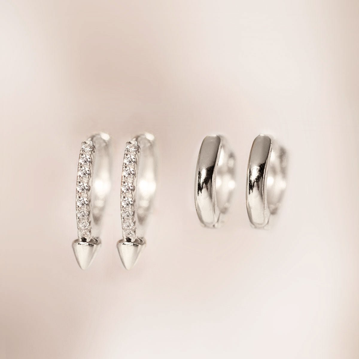 Sterling silver pavé spike huggie hoops shown beside plain silver huggies, close-up detail