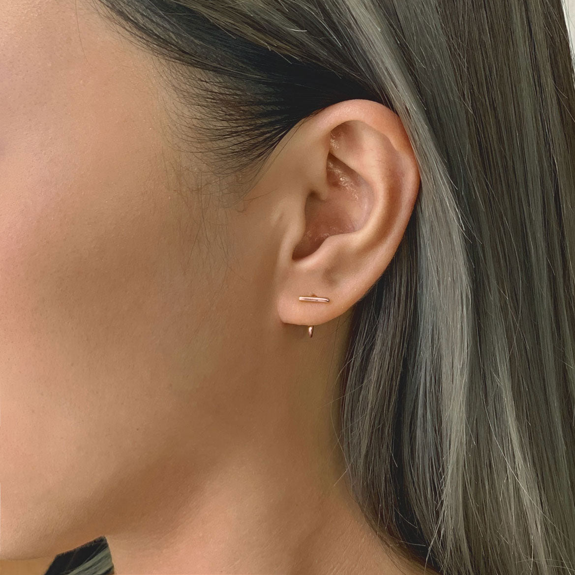 Rose gold vermeil bar huggie earring shown on a model's lobe
