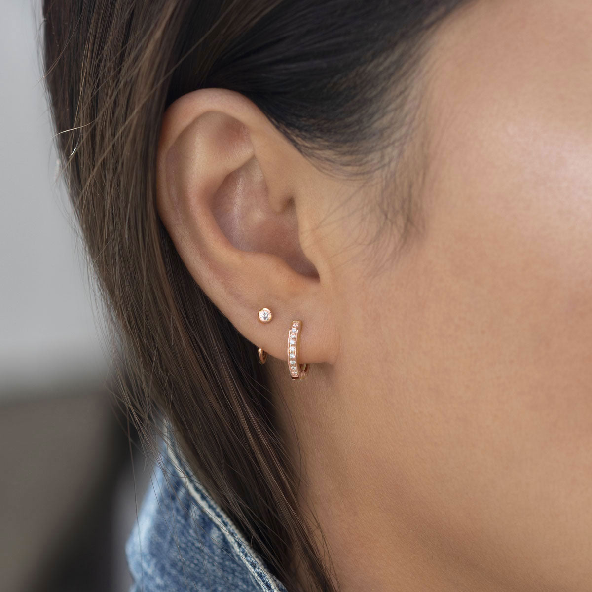 Rose gold vermeil bezel-set white zirconia stud beside a pavé huggie, shown on a model's lobe